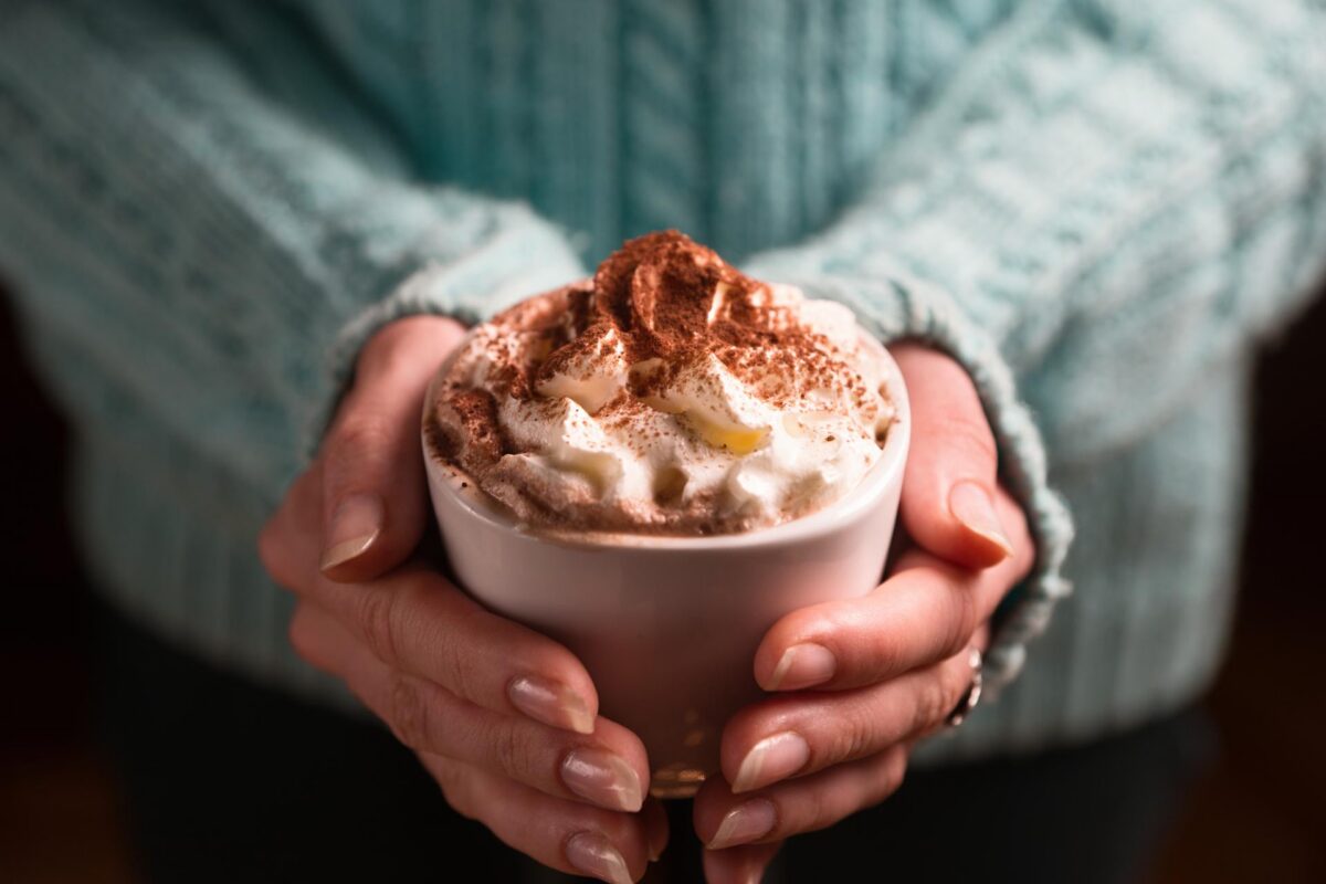 Warm cinnamon milk coffee topped with whipped cream in a mug