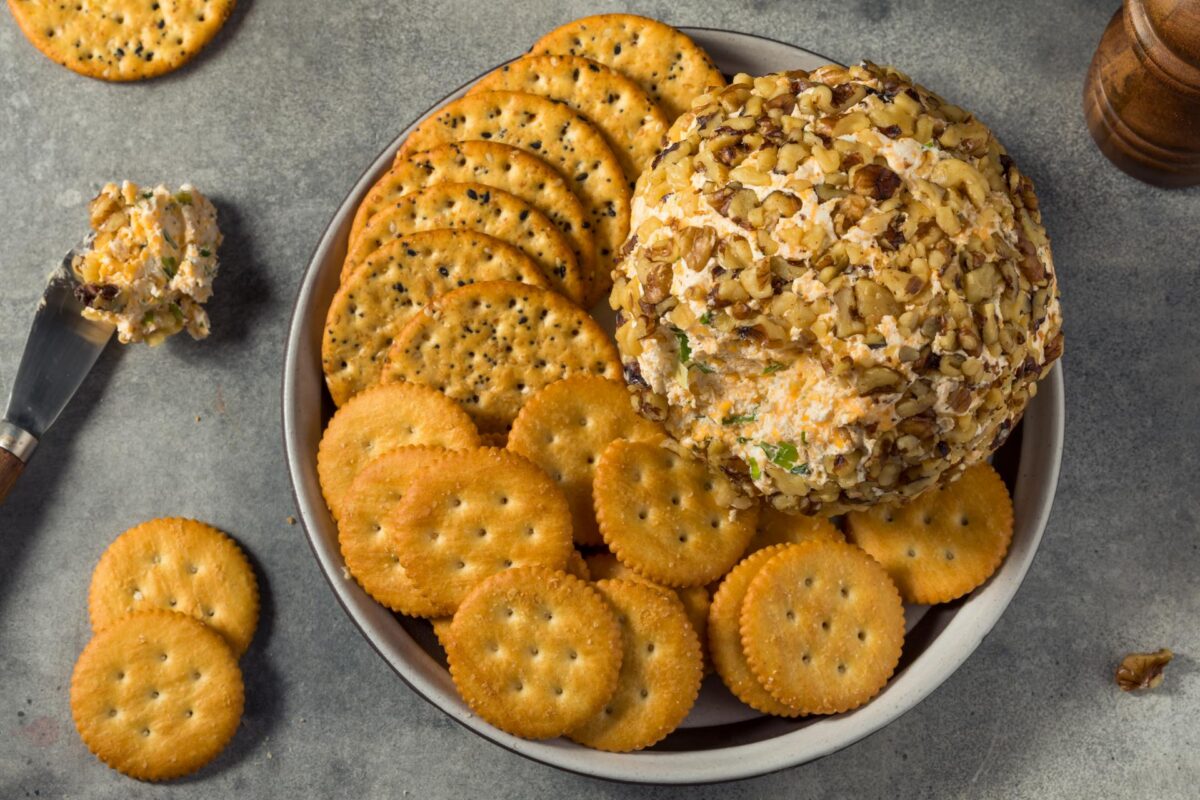 Festive cheese ball coated with bacon, cheddar, pecans, and green onions served as a holiday appetizer